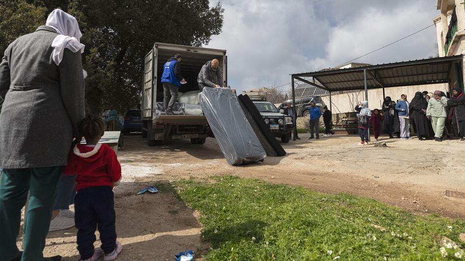 Des travailleurs de l'Organisation internationale pour les migrations (OIM) distribuent des matelas à une famille au Liban