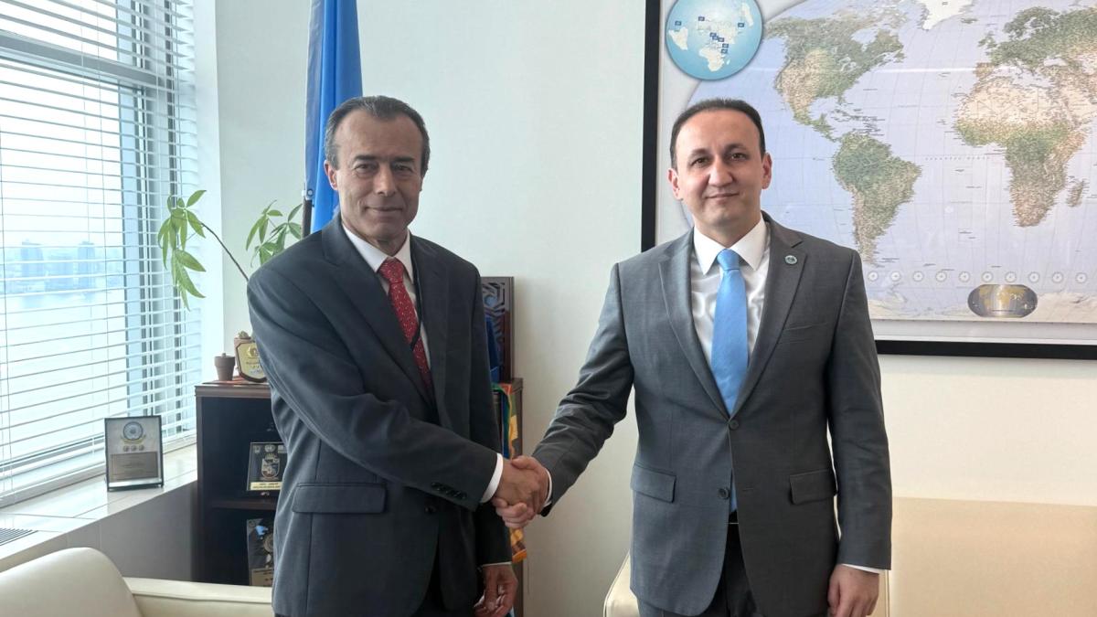 ASG Khaled Khiari and SCO Deputy Secretary-General Ahmad Saidmurodzoda shake hands.