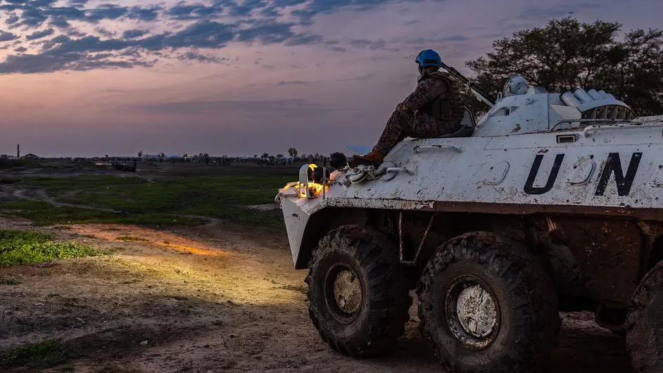 UN  peacekeeper sat on a un vehicle staring at sunset.