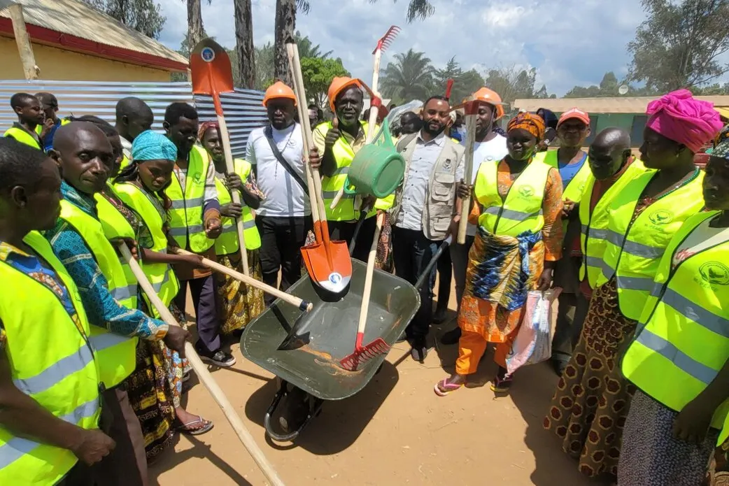 Former combatants, both men and women, receive tools suitable for farming in community fields.