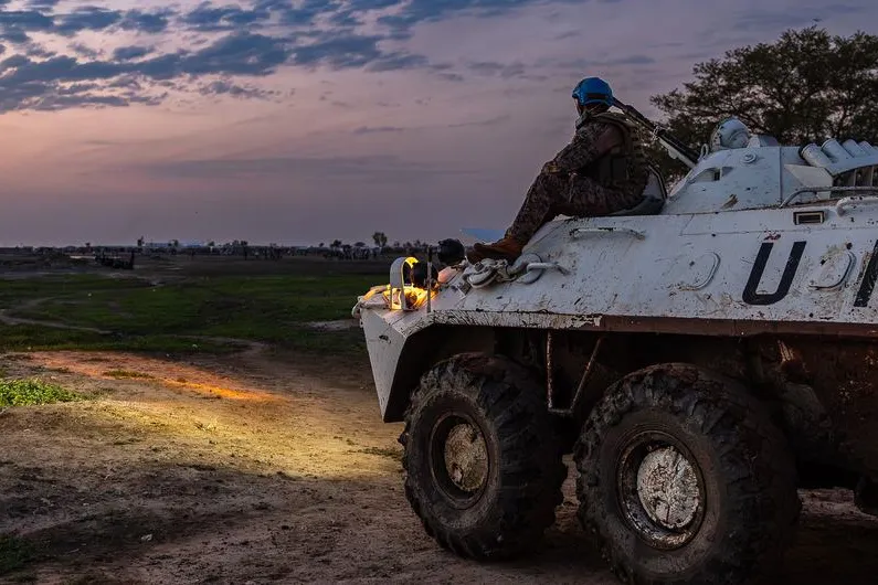 UN peacekeeper sat on a un vehicle staring at sunset.