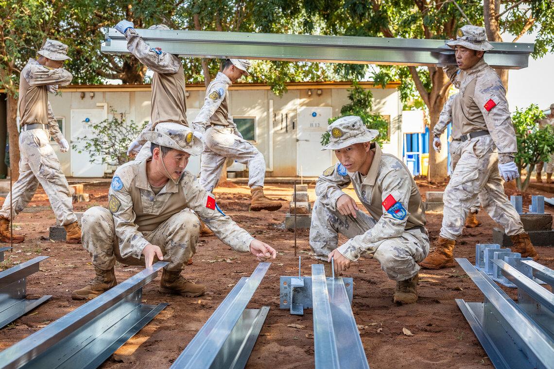 A group of soldiers carry and examine large metal beams